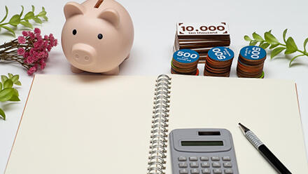 電卓とペンとノート、子豚の貯金箱